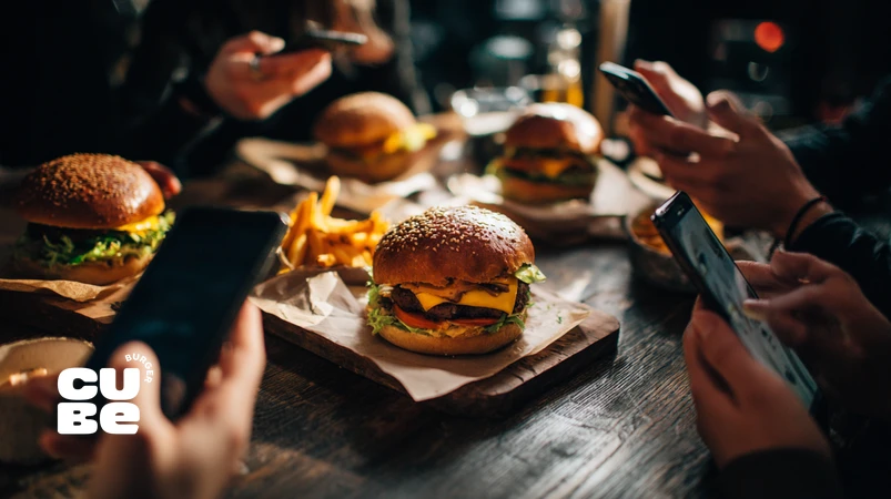 گروهی از مشتریان فعال در یک فستفود تخصصی برگر در حال ثبت تجربه و تولید محتوا برای جامعه برند کیوب برگر