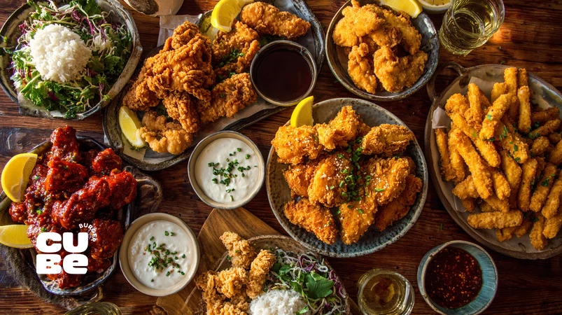 انواع سبک‌های مرغ سوخاری از آمریکایی کرانچی تا کره‌ای تند و کارائه‌گه ژاپنی روی میز چیده شده، همراه استریپس فست‌فودی و نسخه خانگی ایرانی برای راهنمای کامل سبک‌های مرغ سوخاری